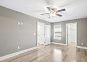 Thumbnail 14 of 24 - A room with a ceiling fan and wooden flooring.