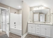 Thumbnail 15 of 24 - A bathroom with a white tub and vanity.