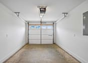 Thumbnail 19 of 24 - A white garage with a closed white door and a white ceiling.