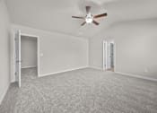 Thumbnail 16 of 29 - A room with a ceiling fan and carpeted floor.