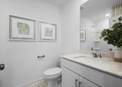 Thumbnail 44 of 49 - A white bathroom with a toilet, sink, and mirror.