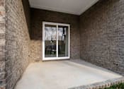 Thumbnail 45 of 49 - A patio with a glass door and a brick wall.