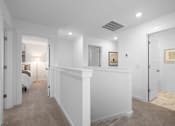 Thumbnail 37 of 49 - A hallway with a white wall and a carpeted floor.