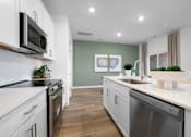 Thumbnail 21 of 49 - A modern kitchen with white cabinets and stainless steel appliances.