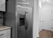 Thumbnail 23 of 49 - A modern kitchen with a stainless steel refrigerator and white cabinets.