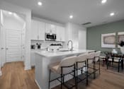 Thumbnail 24 of 49 - A modern kitchen with white cabinets and a large island.