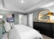 Thumbnail 35 of 49 - A bedroom with a large bed and a dresser with a lamp on top.