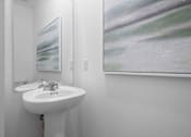 Thumbnail 38 of 49 - A white sink in a bathroom with a painting on the wall.