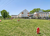 Thumbnail 12 of 12 - A red object is in the foreground of a grassy field with a white building in the background.