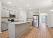 Thumbnail 5 of 16 - A kitchen with wooden floors and white cabinets.