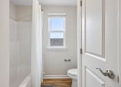 Thumbnail 8 of 16 - A white bathroom with a toilet, a tub, and a window.