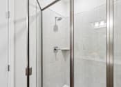 Thumbnail 9 of 16 - A shower area with a glass door and a shower head.