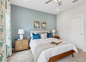 Thumbnail 10 of 16 - A bedroom with a large bed, two nightstands, and a ceiling fan.