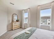 Thumbnail 11 of 16 - A bedroom with a large bed and a window with a view of buildings outside.
