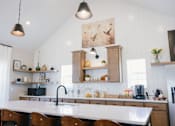 Thumbnail 14 of 16 - A kitchen with a white countertop and wooden chairs.