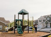 Thumbnail 15 of 16 - A woman is standing in front of a playground.
