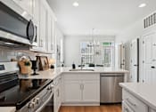 Thumbnail 3 of 13 - A modern kitchen with white cabinets and stainless steel appliances.