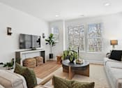 Thumbnail 4 of 13 - A living room with a white couch, a wooden coffee table, and a flat-screen TV mounted on the wall.