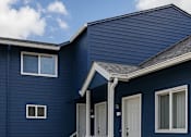 Thumbnail 11 of 11 - A blue house with a white picket fence and a flower bed in front.