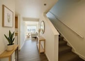 Thumbnail 1 of 11 - A hallway with a staircase and a mirror on the wall.