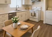 Thumbnail 2 of 11 - A kitchen with a table set for two with a vase of white flowers.