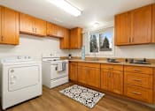 Thumbnail 9 of 11 - A kitchen with wooden cabinets and a white oven.
