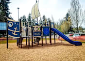 Thumbnail 13 of 13 - A playground with a slide and a wooden structure with a blue and white anchor design.