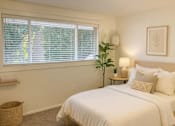 Thumbnail 2 of 13 - A bedroom with a large bed and a window with blinds.
