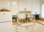 Thumbnail 3 of 13 - A kitchen with white cabinets and a wooden countertop.