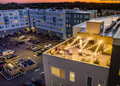 Thumbnail 22 of 23 - A parking lot is in front of a building with a lit up patio.