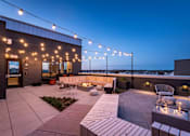 Thumbnail 21 of 23 - A rooftop patio with a fire pit and seating area.