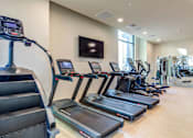 Thumbnail 16 of 23 - A gym with treadmills and elliptical machines.
