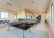 Thumbnail 17 of 23 - A ping pong table is in the middle of a room with a blue rug.
