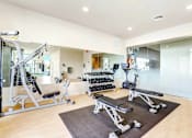 Thumbnail 18 of 23 - A spacious home gym with a variety of equipment including a treadmill, weights, and a bench press.