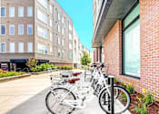 Thumbnail 20 of 23 - Two bicycles are parked next to a brick building.