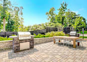 Thumbnail 8 of 23 - A patio with a table and chairs and a grill.
