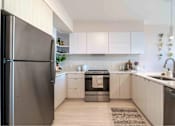 Thumbnail 1 of 23 - A modern kitchen with a refrigerator on the left and a sink on the right.