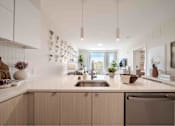 Thumbnail 3 of 23 - A modern kitchen with a stainless steel dishwasher and wooden cabinets.