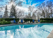 Thumbnail 14 of 16 - a swimming pool with blue chairs and trees in the background