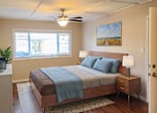 Thumbnail 2 of 34 - A bedroom with a bed, nightstand, and a painting on the wall.