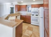 Thumbnail 12 of 54 - View of kitchen with brown cabinets, white appliances, stone counters, tile flooring, and recessed lighting