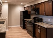 Thumbnail 16 of 19 - A kitchen with black appliances and wooden cabinets.