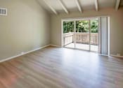 Thumbnail 28 of 56 - A room with wooden flooring and a sliding glass door leading to a balcony.