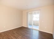 Thumbnail 60 of 61 - A room with wooden floors and a sliding glass door leading to a balcony.