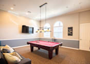 Thumbnail 21 of 61 - A pool table in a room with a couch and a television.