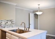 Thumbnail 16 of 25 - A kitchen with a white counter top and a silver sink.