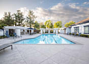 Thumbnail 5 of 61 - A large outdoor swimming pool surrounded by lounge chairs and trees.