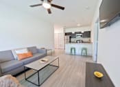 Thumbnail 50 of 66 - A modern living room with a grey sofa, a glass coffee table, and a flat screen TV mounted on the wall.