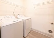 Thumbnail 62 of 66 - A white washing machine and dryer in a small laundry room.