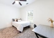 Thumbnail 51 of 66 - A bedroom with a bed, table, and chair.